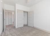 Thumbnail 15 of 46 - a bedroom with white walls and doors and a carpeted floor