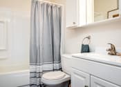 Thumbnail 11 of 26 - A white bathroom with a toilet, sink, and shower curtain.