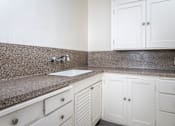 Thumbnail 34 of 52 - A kitchen with white cabinets and a granite countertop.
