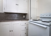 Thumbnail 46 of 52 - A white stove sits in a kitchen with white cabinets.