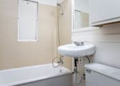 Thumbnail 29 of 52 - A white sink is mounted on a pipe in a bathroom.