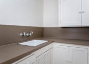 Thumbnail 32 of 52 - A kitchen with brown countertops and white cabinets.
