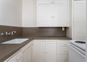 Thumbnail 31 of 52 - A kitchen with white cabinets and a stove top oven.