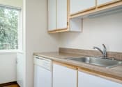 Thumbnail 18 of 26 - A kitchen with a white dishwasher and a stainless steel sink.