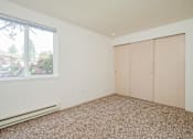Thumbnail 22 of 26 - A room with a carpeted floor, two closet doors, and a window with a view of a garden outside.