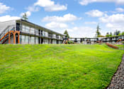Thumbnail 23 of 26 - A modern building with a green lawn in front.