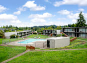 Thumbnail 22 of 26 - A large building complex with a pool in the foreground.