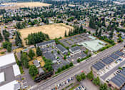 Thumbnail 2 of 13 - A parking lot is surrounded by trees and buildings.