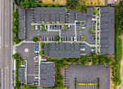 Thumbnail 1 of 13 - A parking lot with cars and a building in the background.
