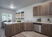 Thumbnail 10 of 13 - A kitchen with wooden cabinets and a stainless steel dishwasher.