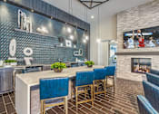 Thumbnail 7 of 11 - A modern kitchen with blue chairs and a fireplace at Crabtree Lakeside Apartments, Raleigh, NC, 27612