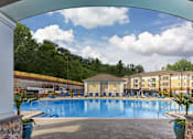 Thumbnail 6 of 11 - A large swimming pool surrounded by a stone wall and a white pillar at Crabtree Lakeside Apartments, North Carolina
