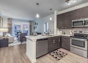 Thumbnail 3 of 11 - A modern kitchen with a large island and stainless steel appliances at Crabtree Lakeside Apartments, Raleigh, 27612