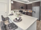 Thumbnail 2 of 11 - A modern kitchen with a white countertop and dark brown cabinets at Crabtree Lakeside Apartments, Raleigh, NC