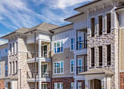 Thumbnail 10 of 11 - A row of modern apartment buildings with balconies and multiple stories at Crabtree Lakeside Apartments, Raleigh, North Carolina