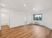 Thumbnail 30 of 45 - a living room with white walls and wood floors and a window