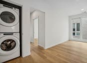 Thumbnail 27 of 45 - a white laundry room with a washing machine and a wood floor