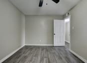 Thumbnail 11 of 20 - an empty living room with wood flooring and a white door at The Crossings at Montrose Apartments, San Antonio, Texas