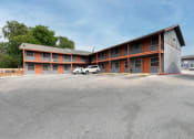 Thumbnail 4 of 20 - a motel with a parking lot in front of a building at The Crossings at Montrose Apartments, San Antonio, TX
