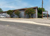 Thumbnail 2 of 20 - a large white building with trees in front of it on a street at The Crossings at Montrose Apartments, Texas, 78223