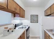 Thumbnail 30 of 37 - A kitchen with a white fridge and wooden cabinets.
