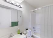 Thumbnail 32 of 37 - A white bathroom with a green towel and a green bottle on the sink.