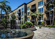 Thumbnail 20 of 57 - A fountain in the middle of a courtyard surrounded by buildings and palm trees at Purl Apartments, San Diego, CA, 92108