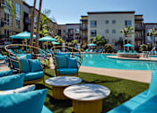 Thumbnail 15 of 57 - A pool area with blue chairs and a yellow table at Purl Apartments, San Diego, California