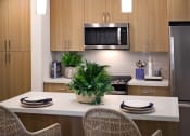 Thumbnail 12 of 26 - a kitchen with a counter and a table with chairs at Luma at El Corazon Apartments, Oceanside, CA 92056