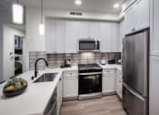 Thumbnail 18 of 26 - a kitchen with white cabinets and stainless steel appliances at Luma at El Corazon Apartments, California
