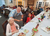 Thumbnail 55 of 59 - A group of people are sitting around a long table with a festive meal  at Savannah Grand of Sarasota, Sarasota, 34238.