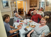 Thumbnail 57 of 59 - A group of people are sitting around a table with plates of food in front of them  at Savannah Grand of Sarasota, Sarasota, FL.