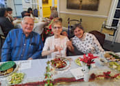 Thumbnail 54 of 59 - Three people sitting at a table with plates of food in front of them  at Savannah Grand of Sarasota, Sarasota, FL.