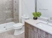 Thumbnail 7 of 19 - A white toilet sits next to a walk-in shower in a bathroom.