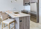 Thumbnail 16 of 19 - A kitchen with a white countertop and wooden cabinets.