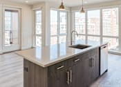 Thumbnail 17 of 19 - A modern kitchen with a large island and wooden cabinets.