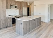Thumbnail 19 of 19 - A kitchen with a white countertop and wooden cabinets.