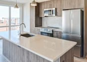 Thumbnail 13 of 19 - A modern kitchen with a marble countertop and stainless steel appliances.