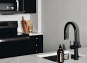 Thumbnail 4 of 10 - A modern kitchen with black cabinets and a white countertop.