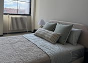 Thumbnail 8 of 10 - A bed with a grey comforter and pillows is in front of a window.
