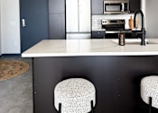 Thumbnail 10 of 10 - A kitchen with a white countertop and black cabinets.