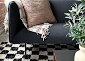 Thumbnail 3 of 10 - a black couch with a pillow and a blanket on it
