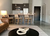 Thumbnail 1 of 19 - A modern living room with a black coffee table and a white sculpture on it.