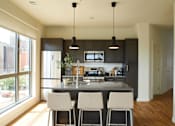 Thumbnail 109 of 113 - a large kitchen with black cabinets and a counter with four chairs at The Audubon New Haven, New Haven, CT, 06511