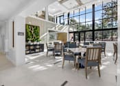Thumbnail 21 of 24 - A modern dining room with a glass wall and a tree in the background.