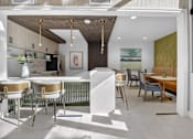 Thumbnail 14 of 24 - A modern kitchen with a dining table and chairs.