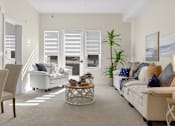 Thumbnail 5 of 24 - A living room with a white sofa, a wooden chair, and a coffee table.