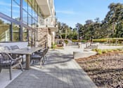 Thumbnail 6 of 24 - A patio with a table and chairs is surrounded by a garden.