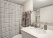 Thumbnail 28 of 38 - a bathroom with a shower and a sink and a mirror