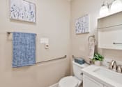 Thumbnail 24 of 25 - A bathroom with a toilet, sink, and a blue towel hanging on the wall.